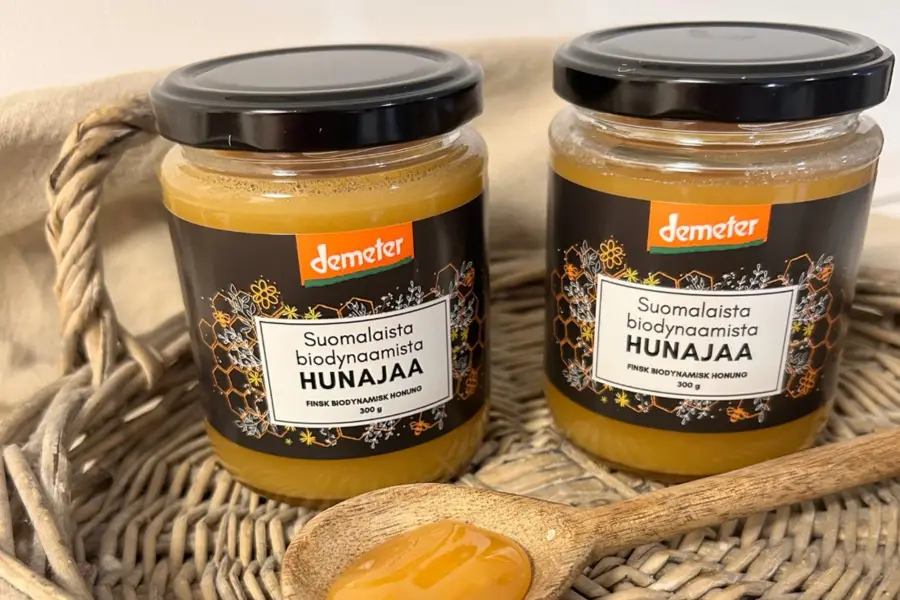 suomalainen biodynaaminen hunaja, demeter hunaja, demeter, kaksi hunajapurkkia ja puulusikka, hunajaa lusikassa, rottinkitarjotin